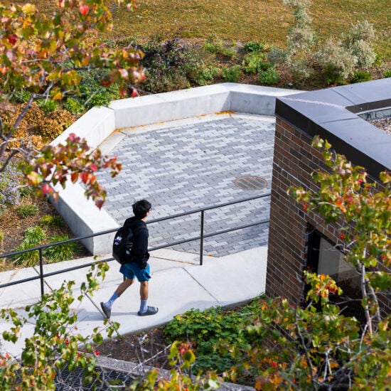 Student walking on UIC's campus outside of the Institute for the Humanities